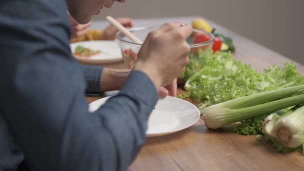Un hombre comiendo una ensalada vegetariana de verduras frescas. Nutrición deportiva y alimentación saludable. Cena en casa - Metraje, vídeo