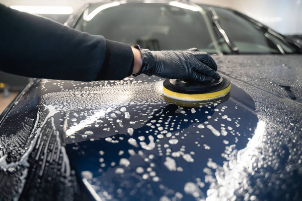 Ο άνθρωπος καθαρίζει κουκούλα αυτοκινήτου με σφουγγάρι κύκλο. Προετοιμασία auto για γυάλισμα. - Φωτογραφία, εικόνα