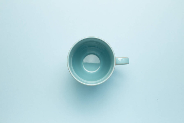 Empty mug cup on sky blue background. top view, copy space - 写真・画像