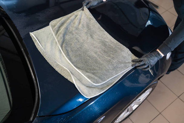 Trabajador de lavado de coches limpia el coche después de lavar con toalla de microfibra. Lavado profesional de automóviles - Foto, Imagen