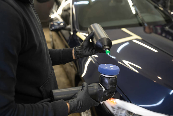 Detailing master applies car polish paste to the polisher. Vehicle paintwork polishing concept - Photo, Image
