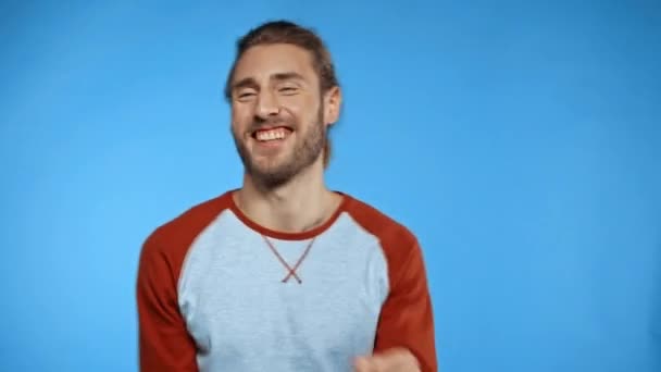 Mann lächelt, während er isoliert auf blauem Grund tanzt - Filmmaterial, Video