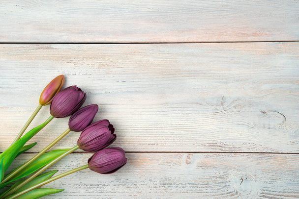 Фіолетові тюльпани на світлому дерев'яному тлі. Вид зверху з пробілом для копіювання
. - Фото, зображення