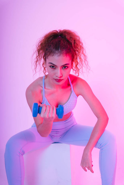 Healthy young asian curly hair woman using dumbbells in gym studio. - 写真・画像