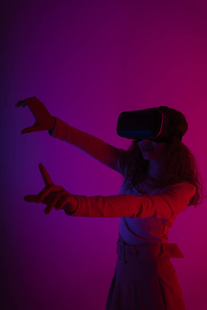 Happy woman wear virtual reality VR goggles in neon light background.  - Photo, Image