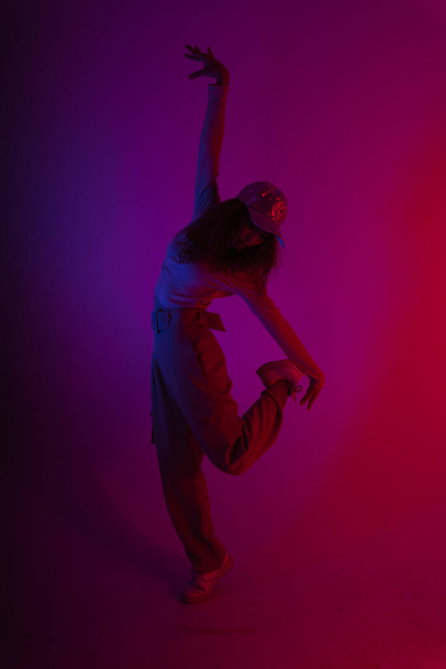 Portrait of young hipster woman dancing in dark neon light background. - Fotó, kép
