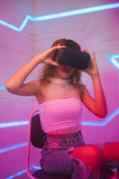 Malli nuori kihara tukka nainen käyttää lasit virtuaalitodellisuus VR tulevassa huoneessa. - Valokuva, kuva