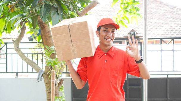 delivery man delivers the box to the customer and ok gesture - Photo, Image