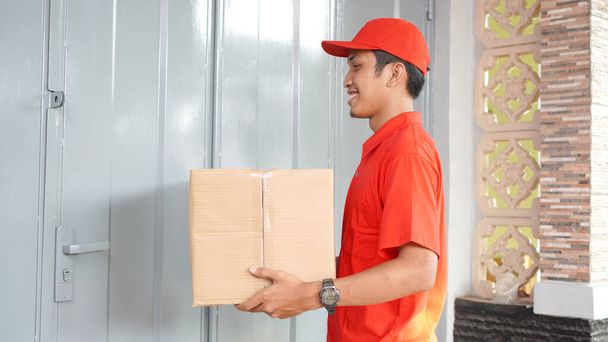 ο διανομέας παραδίδει το κουτί μπροστά από το σπίτι του πελάτη - Φωτογραφία, εικόνα