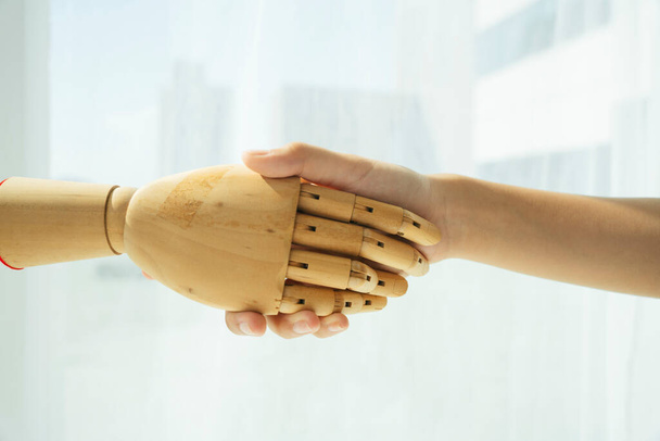 木製のサイボーグロボットと人間の握手の手. - 写真・画像