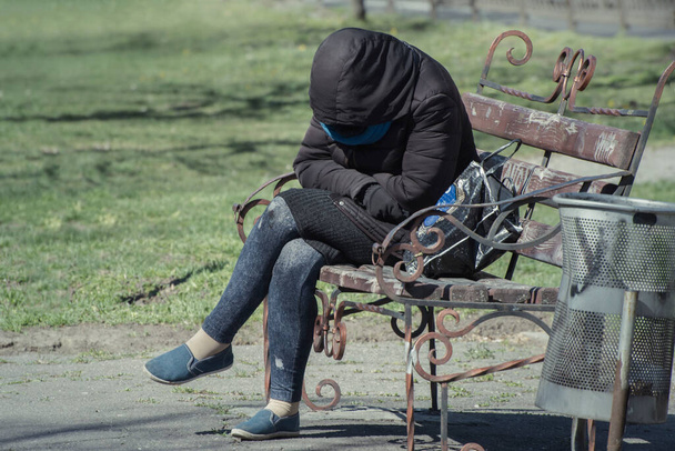 Бездомная нищенка на скамейке в городском парке. Депрессия в жизни человека. - Фото, изображение