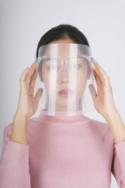 Close up - New normal fashion portrait. Asian thai long dark hair woman in pink sweater wearing face shield isolate over white. - Фото, зображення