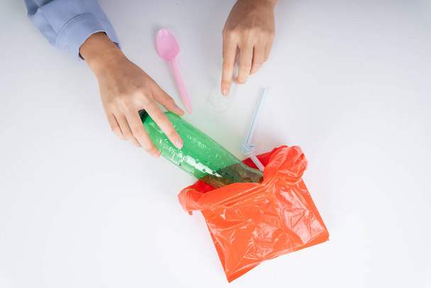 Le mani della donna mettono i rifiuti di plastica in un sacchetto di plastica per riciclare la progressione. - Foto, immagini