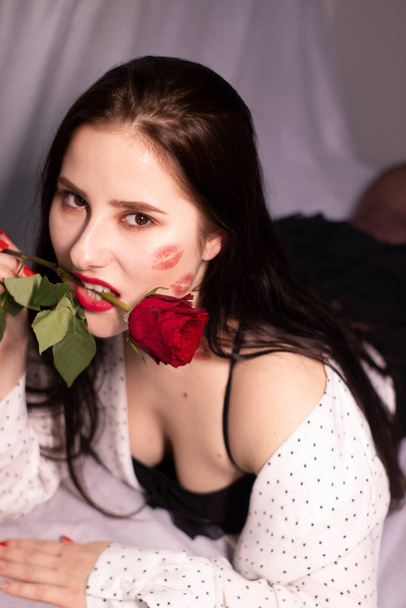 femme brune sexy avec baisers, marques de rouge à lèvres sur son visage et son cou, avec rose rouge. petite amie, rencard, relation. lesbienne gay. lgbt. espace de copie - Photo, image