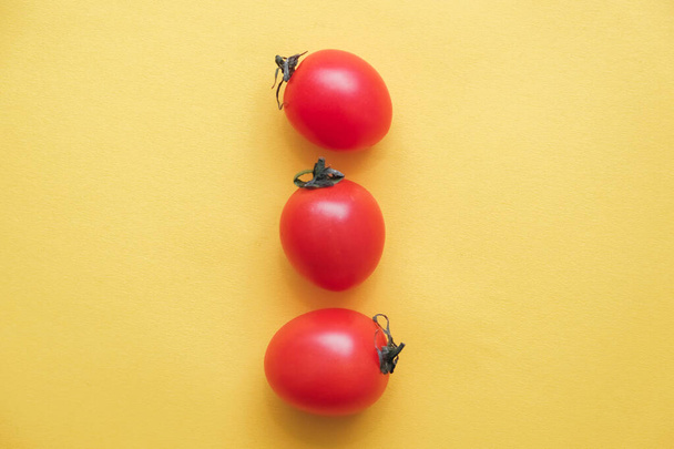 Red tomatos vegetable on a yellow background. Top view. Minimalist Style. Copy, empty space for text. - Photo, Image