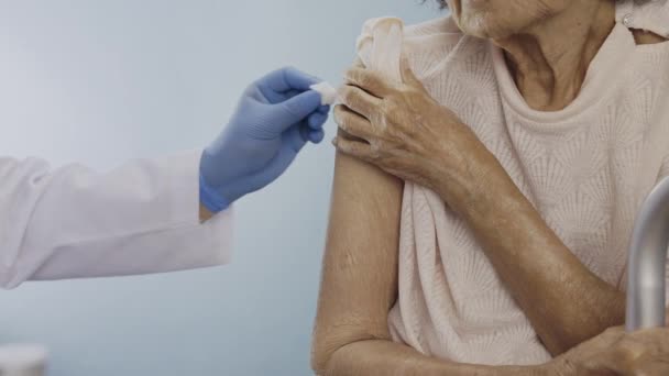 Acercarse médico haciendo la inyección de vacuna a la mujer mayor. - Imágenes, Vídeo
