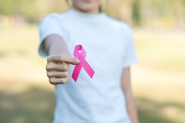 октябрь Месяц награждения за рак молочной железы, взрослая женщина, держащая за руку розовую ленту для поддержки живущих и больных людей. Концепция Международного дня женщин, матерей и борьбы с раком - Фото, изображение