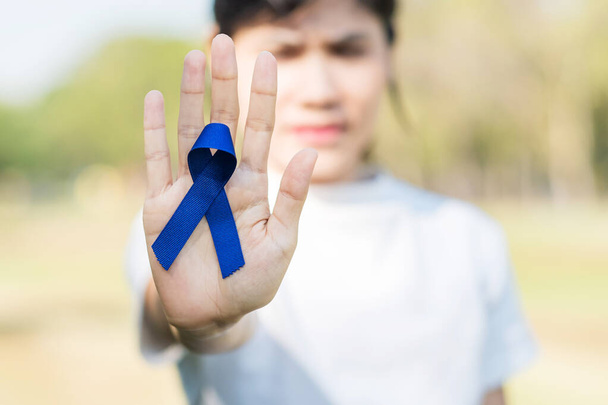Marzo Mes de concientización sobre el cáncer colorrectal, Mujer con cinta azul oscura para apoyar a las personas que viven y enferman. Salud, esperanza y concepto del Día Mundial del Cáncer - Foto, Imagen