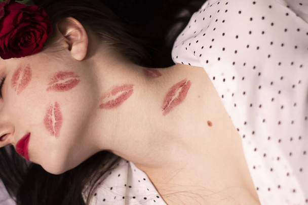 sexy brunette vrouw met kussen, lippenstift markeringen op haar gezicht en nek, met rode roos. vriendin, afspraakje, relatieperiode. lesbische homo. Het spijt me. kopieerruimte - Foto, afbeelding