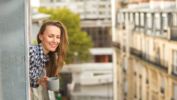 Good morning! Beautiful woman with a cup of coffee enjoying spring or autumn day - Фото, зображення