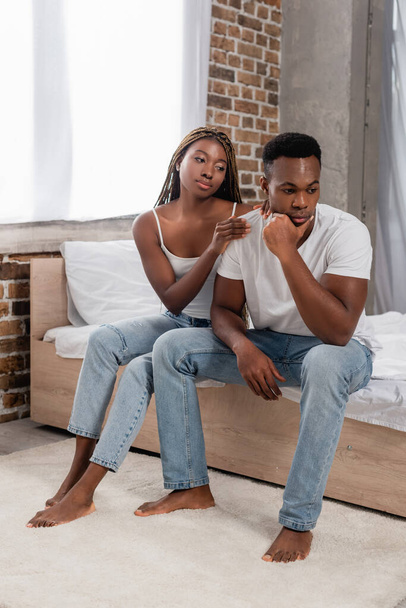 African american woman calming pensive boyfriend on bed  - Photo, Image