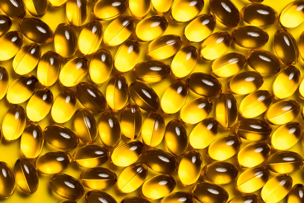 omega 3 vitamins or fish oil scattered on a yellow background. - Foto, Imagen