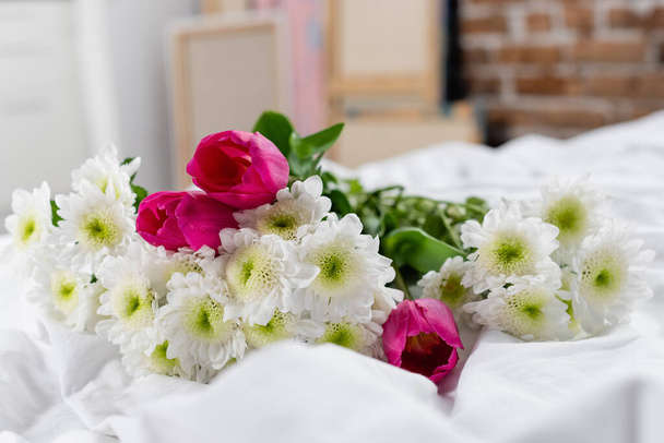 Chrysanthemums and tulips on white bedding on blurred foreground  - Fotografie, Obrázek
