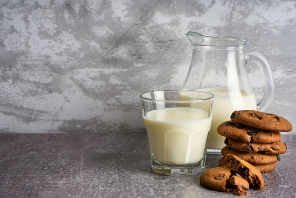 Glass jug and glass with milk on gray background. - Foto, afbeelding