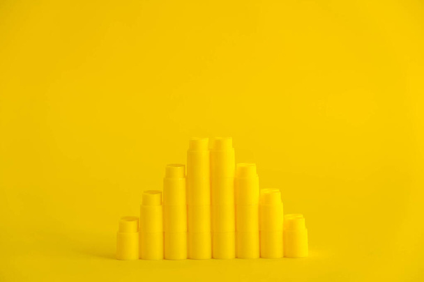 Yellow plastic building blocks in the shape of a pyramid on yellow background. Background of plastic details building blocks. Parts of bright small spare parts for toys. Copy, empty space for text. - Photo, Image