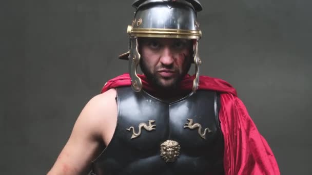 Vakava sotilaallinen roomalainen vetää miekkansa esiin ja poseeraa pimeässä taustassa. - Materiaali, video