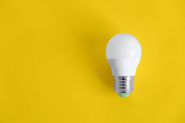 White light bulb on yellow background. Top view. Copy, empty space for text. - Photo, Image