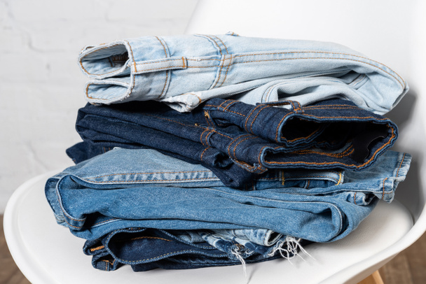 vista da vicino di vari jeans impilati sulla sedia - Foto, immagini