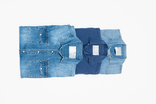 vrchní pohled na různé modré džínové košile na bílém pozadí - Fotografie, Obrázek