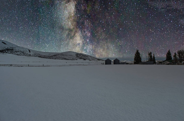 A beautiful shot of snow-covered mountains with the Milky Way galaxy in a starry sky - Фото, изображение