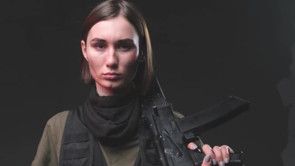 Mercenaire féminine sérieuse avec un fusil sur l'épaule en studio - Séquence, vidéo