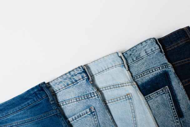 diagonal row of various jeans on white background, top view - Valokuva, kuva