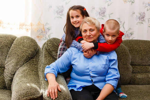 Adulto adulto nietos sonrientes abraza abuela anciana feliz de verla perdiéndola, visita de familiares amorosos disfrutar de la comunicación, abrazo como símbolo de conexión, el amor y el concepto de apoyo - Foto, Imagen