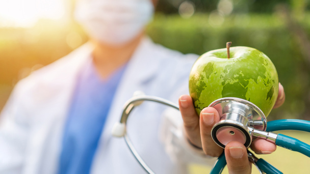 Giornata mondiale della salute, una mela al giorno tiene il medico lontano dal concetto di beneficio per la salute mangiando cibi puliti e nutrienti e una dieta nutrizionale sana con il medico che gestisce la mela verde che dà al paziente - Foto, immagini