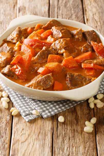 Mafe or Maafe is an authentic African peanut stew made in beef, spicy, creamy peanut butter and tomato sauce closeup in the pan on the table. Vertica - Photo, Image