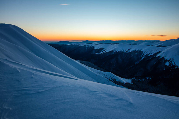 A closeup shot of mountains covered in snow under a sunset sky - Fotografie, Obrázek