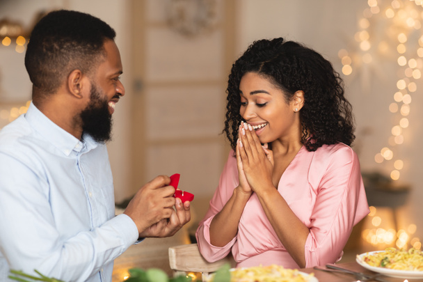 Glimlachend afro man doet aanzoek met ring aan zijn verloofde - Foto, afbeelding