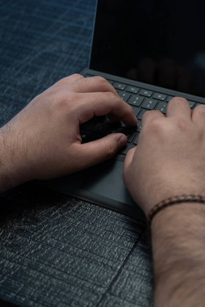 Un colpo verticale delle mani di un maschio utilizzando una tavoletta con una tastiera - Foto, immagini
