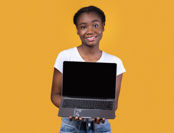 Happy African Woman Wyświetlanie Laptop pusty ekran na żółtym tle - Zdjęcie, obraz