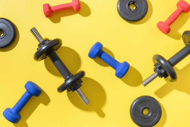 Set of dumbbells on yellow background. Top view, copy space. - Foto, immagini