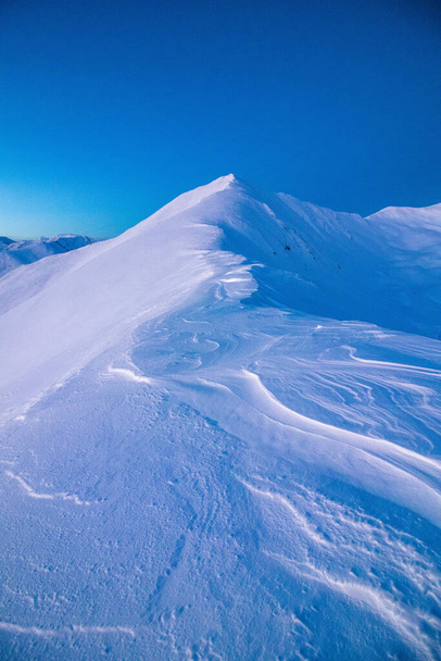 Un colpo verticale di montagne coperte di neve sotto un cielo luminoso - Foto, immagini