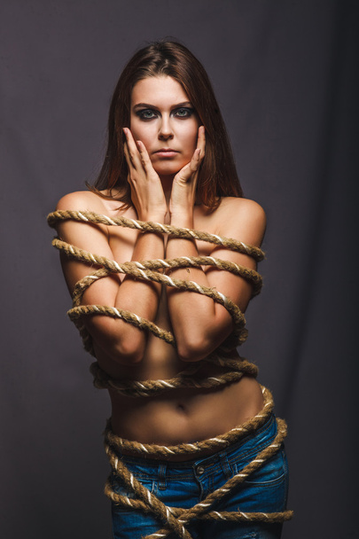 Brunette hostage, captive bound woman with rope prisoner in jean - Photo, image
