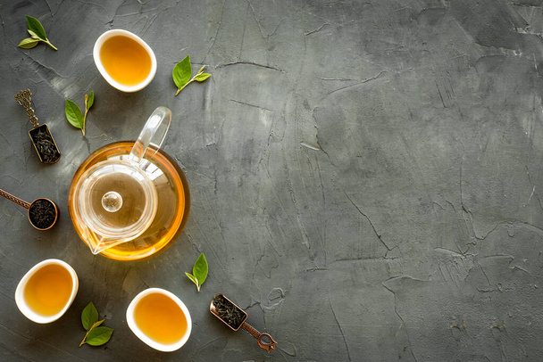 Tea green leaves with teapot and cups, top view. Tea ceremony concept. - Φωτογραφία, εικόνα