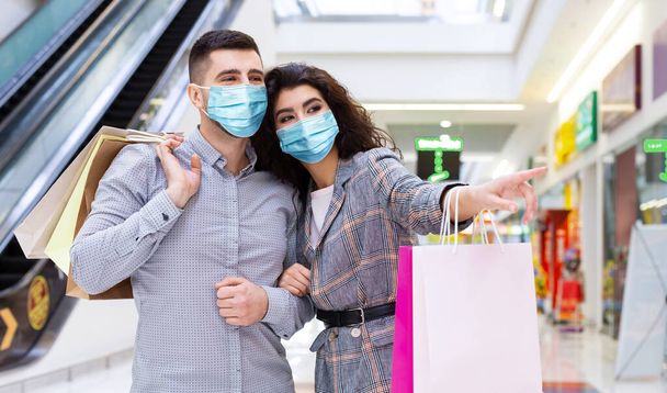 Liebendes Paar mit Gesichtsmasken beim Einkaufen in City Mall - Foto, Bild