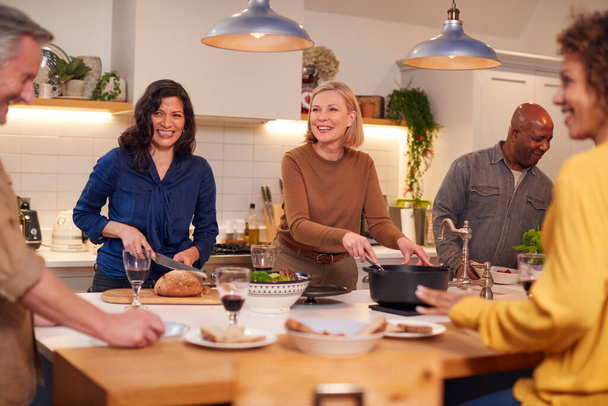 Group Of Mature Friends Meeting At Home Serving Food At Dinner Party And Drinking Wine Together - Photo, Image
