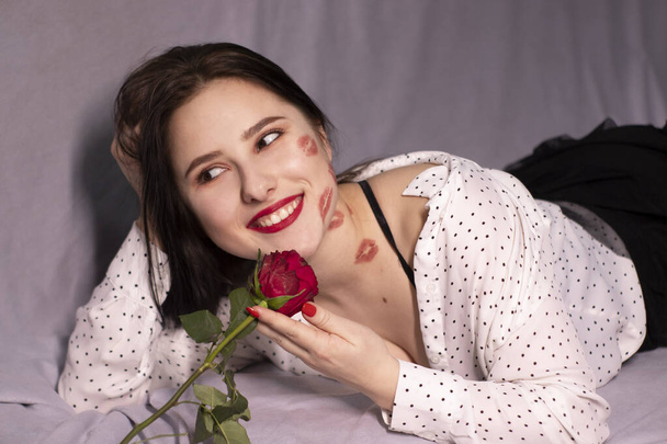 キスをしたセクシーなブルネットの女性、顔と首に口紅のマーク、赤いバラ。彼女とデートとか恋愛とか。コピースペース - 写真・画像